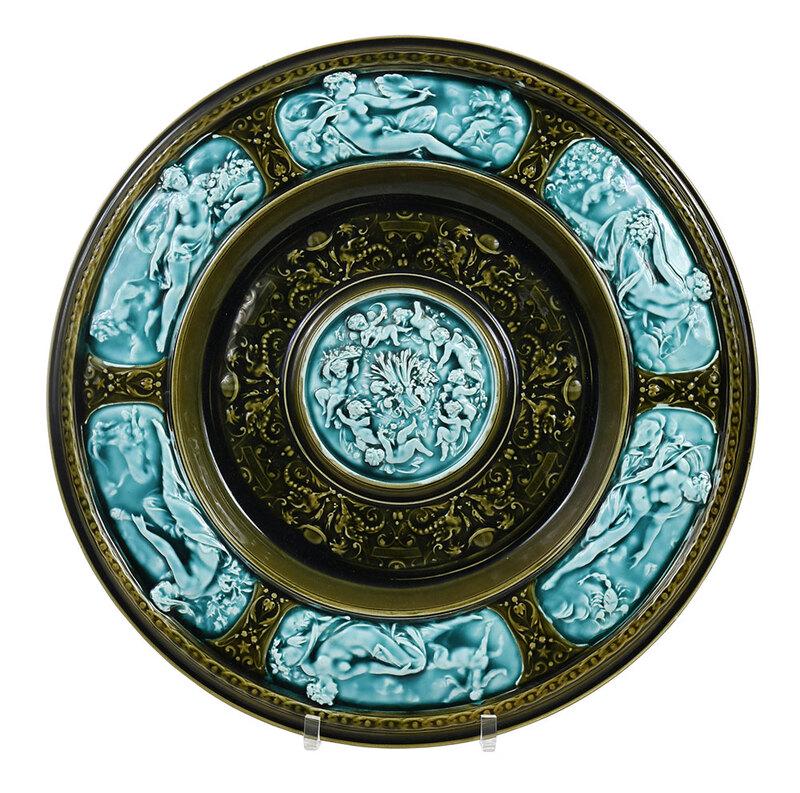Schtz Majolica Glazed Porcelain Zodiac Charger: Austrian, early 20th century, glazed in olive and teal, relief molded neoclassical decoration representing six Zodiac signs from Leo to Capricorn, stamped on base "Schtz/Cilli", with wire display, 19-