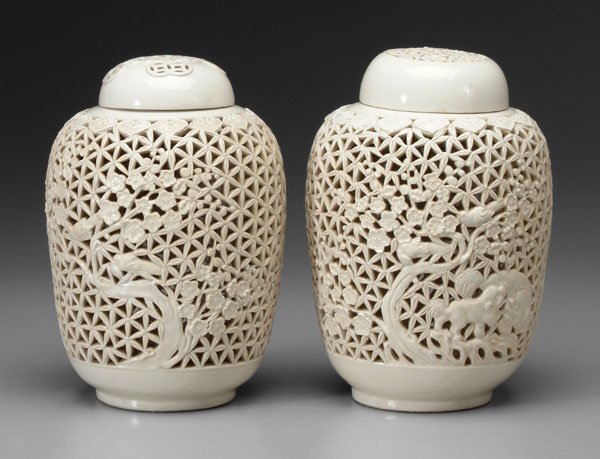 Two Chinese [blanc de chine] jars:: reticulated bodies and lids, one with birds in prunus trees, other with Buddhist lions under prunus trees, bases stamped "China Made", 20th century, 11-1/2 in. Excellent condition. Provenance: Collect
