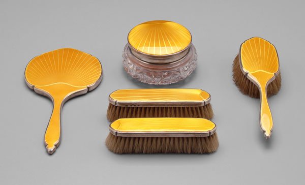 English silver enameled dresser set,: Art Deco with yellow enameled ray decoration: jar with cut glass base, hand mirror, hand brush and two clothes brushes, no monograms, marks for Richard Comyns, London, 1934, (five pieces). Small chips