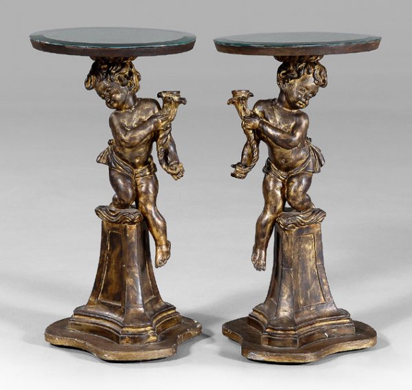 Pair Italian rococo style tables:: each with beveled circular mirrored top over carved and gilt figure of [putto] holding cornucopia, tripod pedestal base, early 20th century, 27 x 14 x 14 in. [Putti] and bases with paint retouch, some