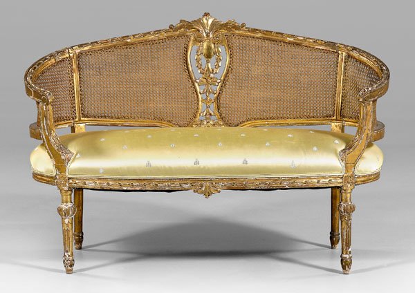 Louis XVI style loveseat,: carved and gilt beech frame with caned back and Fortuny upholstered seat, French, 19th century, 37 x 53-1/2 x 21-1/2 in. Extensive gilding and gesso losses, several breaks and repairs to crest rail, c