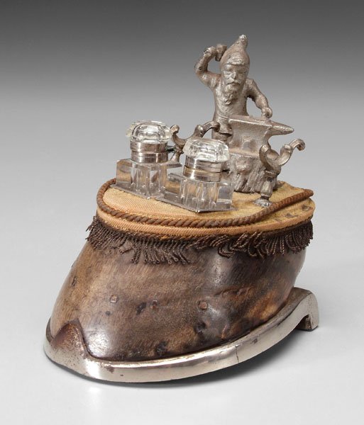 Ink stand,: horse hoof base with horseshoe, top with miniature elf at anvil (probably pewter) behind pen stand, two glass inkwells, probably British, 19th century, 6-1/2 in. Losses to fabric at top, several eleme