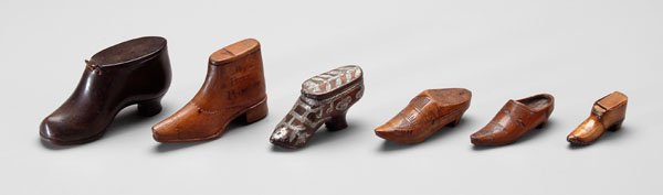 Six miniature shoes,: probably snuff boxes: one heavy black leather, brass studs on heel and sole, [one side of hinge pulled through leather;] one carved wood boot with articulated seams and sliding top, marked "Upper Topa