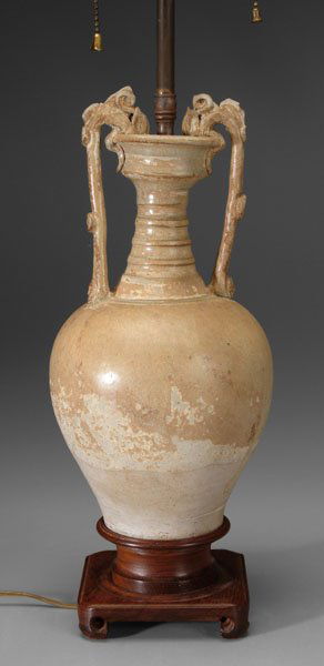 Chinese amphora vase,: ovoid gray clay body with banded and tiered neck, cup-form mouth gripped at rim by dragon-head handles, pale yellow glaze pooling to clear blue glaze at handle ends, bands on neck, Tang dynasty (AD 61