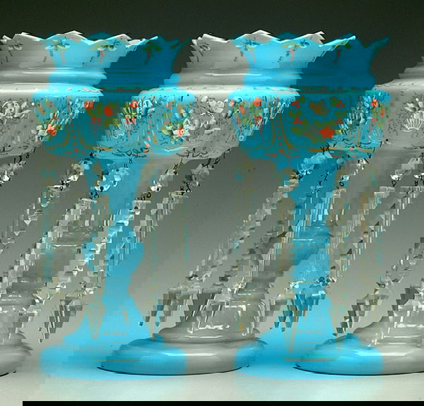 Pair blue glass mantle lusters: splayed crown-form tops, bands of hand-painted polychrome floral and butterfly decorations, blue milk glass, each with eight suspended cut glass prisms with chips, one prism replaced, losses to gildin