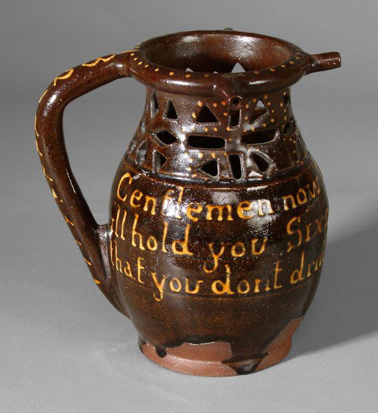 Redware puzzle jug,: cutwork neck and shoulders with dot slip decoration, handle marked "1821", slip-decorated motto "Gentlemen now try your Skill/i'll hold you Sixpence if you Will/that you don't drink unless you Spill",