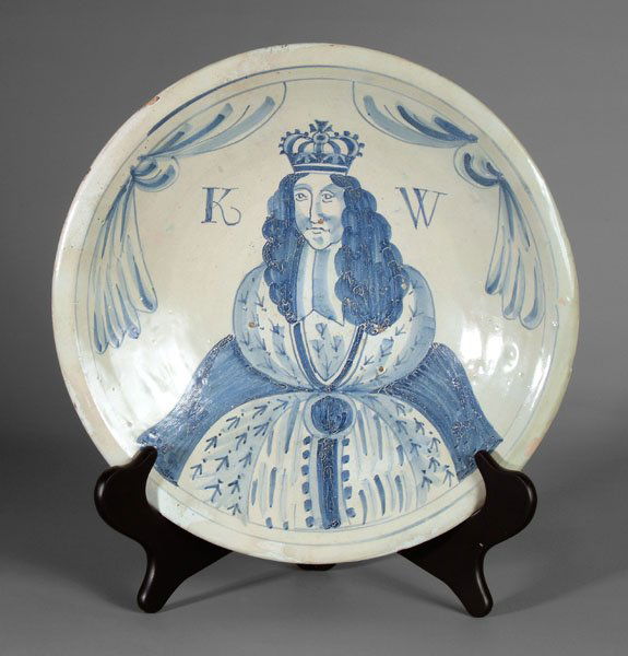 King William Delft charger,: portrait of the crowned king flanked by "K" and "W" with floral drapery borders, British, circa 1690, 14 in. Extensive restoration and resurfacing. Provenance: W. Ted Gossett Collection, 1989. Illustr