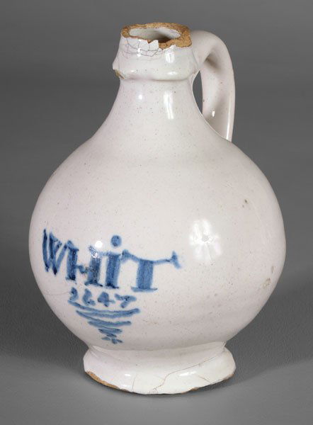 Delft wine bottle,: white-glazed globular form with shaped spout and tapered foot ring, marked in blue "Whit 1647" above a wavy line, Lambeth or London, England, 5-3/4 in. Rim and base chips, several cracks. Provenance: