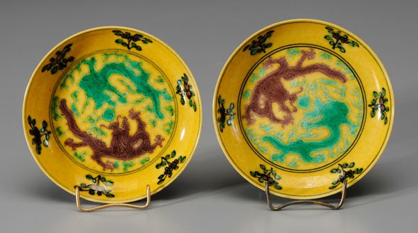 Pair Chinese yellow-ground dishes: interiors with aubergine and green dragons with pearl on a rich yellow ground, border of fruit and flowers, exterior with aubergine and green dragons, [lingzhi,] base with black six-character mark for