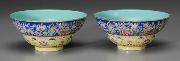 Pair Chinese [famille rose] bowls:: waisted bodies with gently curving sides, turquoise interiors, exteriors with [bajixiang] on blue ground, lotuses and bats on yellow ground, turquoise base with red Qianlong (1735-1795) seal mark, 20t