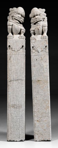 Pair Chinese stone columns:: square-section gray stone topped with mirror image Buddhist lions seated on cloth-draped tables, 20th century, 63 in. Minor repair top one claw, one nose, ears.