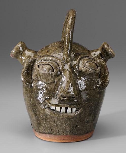 B. B. Craig monkey jug: (Burlon Craig, Lincoln County, North Carolina, 1914-2002), handle above double-spout top, medium olive glaze, broken-china teeth, stamped mark "BB Craig Vale NC", 9-3/4 in. Excellent condition. Proven