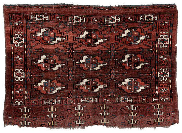 Turkomen rug,: rows of [guls] on faded brick-red ground, 2 ft. 8 in. x 3 ft. Scattered moth damage and related holes, sides frayed with losses, otherwise generally even pile.