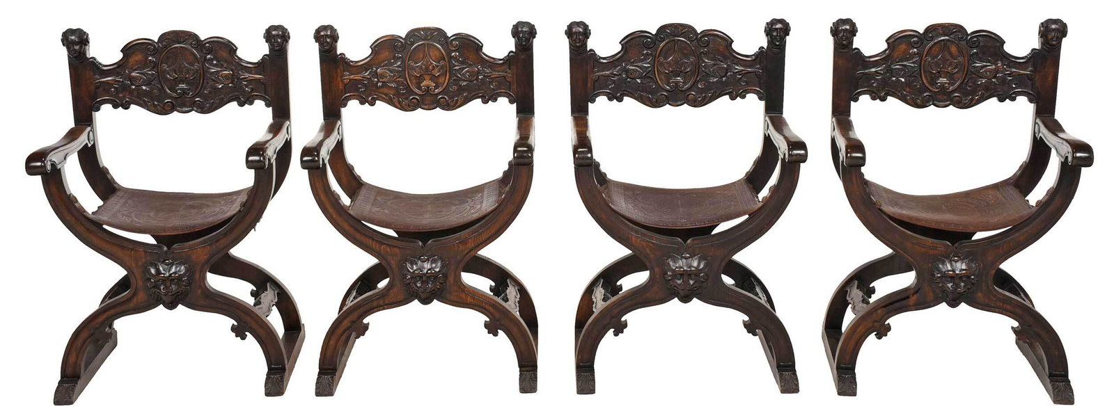 Set of Four Spanish Baroque Style Leather Upholstered: Continental, early 20th century, Savonarola chairs in the Renaissance style, each with mask finials centering a relief carved back, tooled leather seat, mask decorated base, walnut and beechwood frame