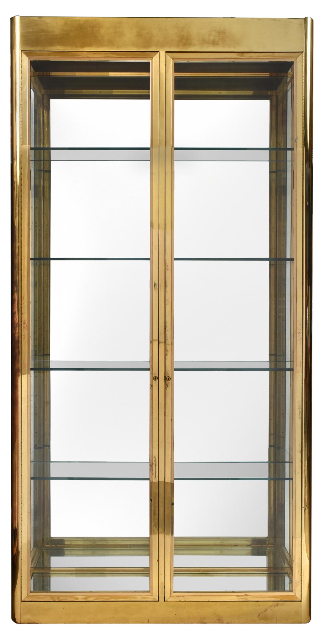 Monumental Brueton Brass Over Steel Display Case: circa 1970, unsigned (attribution), rectangular case in brass plated steel, rounded corners, two glazed doors opening to adjustable shelved interior, lighted top, 108-1/2 x 54 x 16 in.
