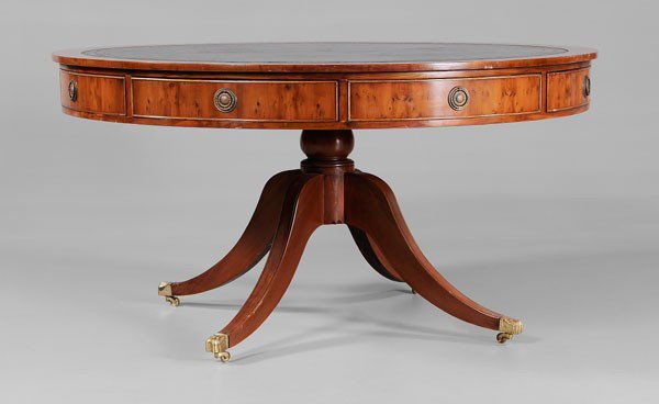 Regency Style Drum Table: modern, yew wood veneer, large scale with tooled black leather top, four drawers and four false drawers, pedestal base with brass casters, 31 x 59-1/2 in., good condition overall with scattered surfac