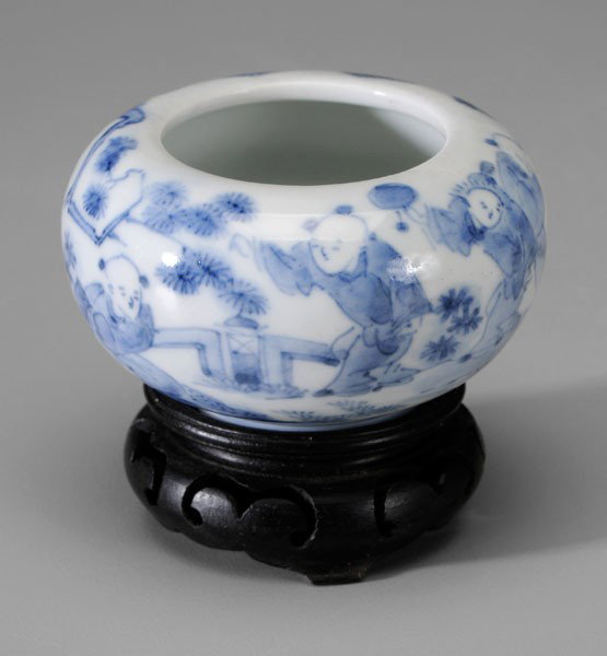 Blue-and-White Porcelain Water Pot: Chinese, late 19th/early 20th century, flattened ovoid, boys playing in a garden, base with two blue concentric circles, 1-7/8 x 3 in., with wood stand, very minor flaws and scratches Provenance: Esta