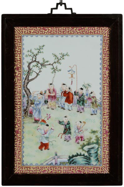 [Famille Rose] Porcelain Plaque: Chinese, 19th century, finely enameled with boys playing in an enclosed garden, several holding Buddhist objects, blue spearhead and yellow-ground border with rose fretwork and dragons, 14-3/4 x 9-3/4