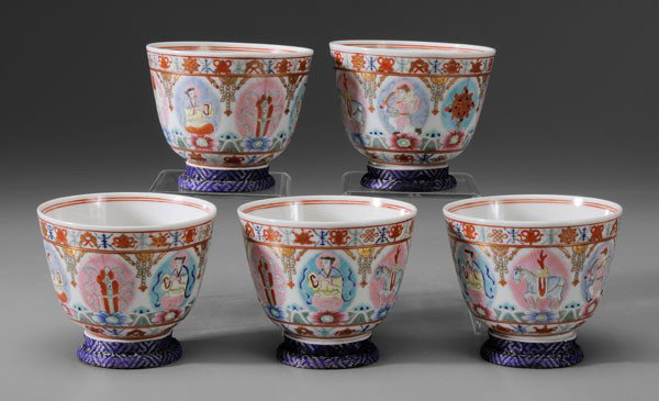 Five [Famille Rose] Porcelain Cups: Chinese, probably Republic period, bell form, interiors with lotus flower, exteriors with Buddhist figures and objects on leaf-shaped medallions supported by wave-borne flowers between borders of [baj