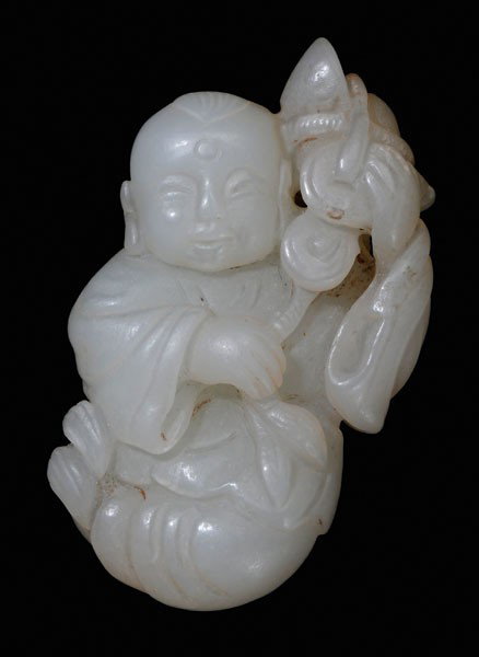Jade Toggle: Qing Dynasty, translucent white [Xinjiang] jade, boy seated with crossed legs, a string of cash and a [tael] on and over his left shoulder, one coin with natural fissure, 56 grams, 2-3/8 x 1-1/2 x 7/8