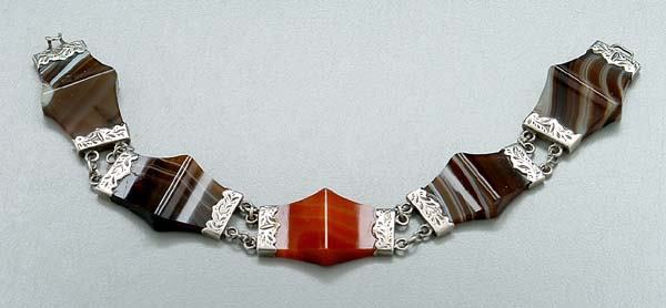 Scottish agate and silver bracelet,: four brown and white and one orange-red expanded center agate cabochons, engraved silver end mounts and links, tested .900 or higher, glue residue, minor edge chips, one stone with surface cracks (pos