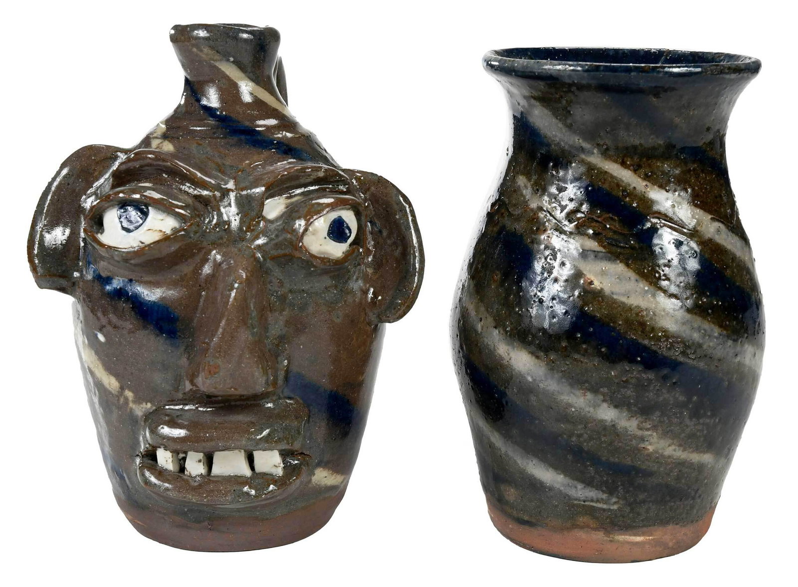 Two Pieces of Burlon Craig Pottery: (Vale, North Carolina, 1914-2002) blue, white and tan swirl jug, applied facial features, inset kaolin eyes, cobalt pupils, broken china teeth, wavy line decoration at shoulder, applied strap handle, 