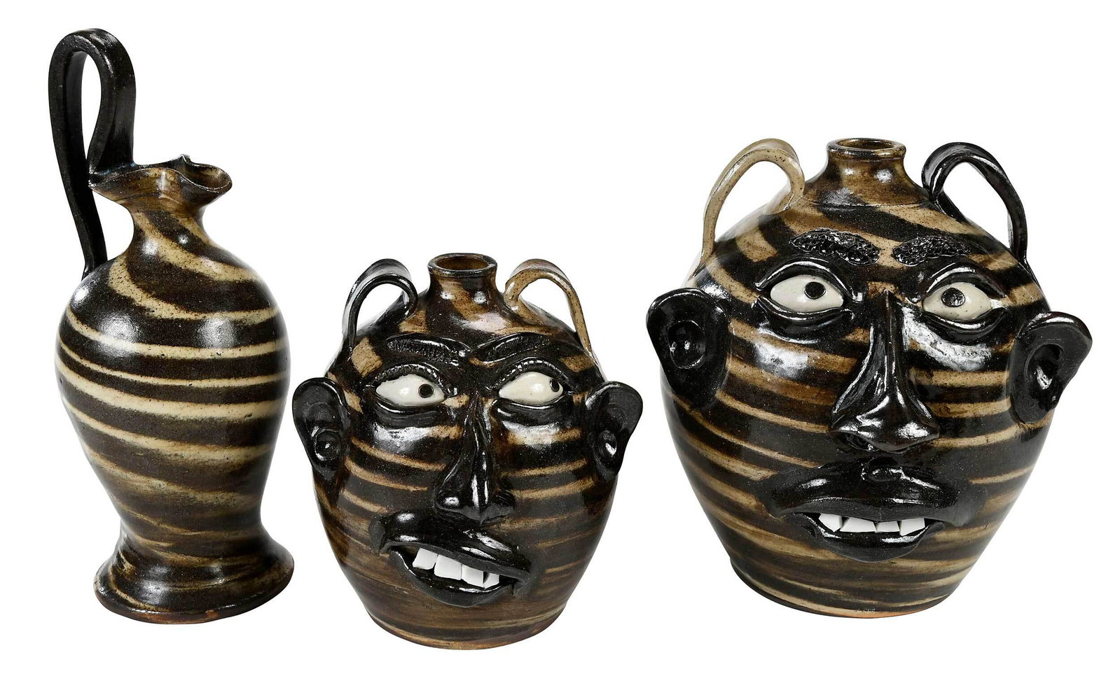 Three Pieces of Wayne Hewell Pottery: (Gillsville, Georgia, circa 2000's) face jugs with brown and tan swirl glazes, applied facial features, inset kaolin eyes with brown clay pupils, broken china teeth, pairs of applied strap handles, st