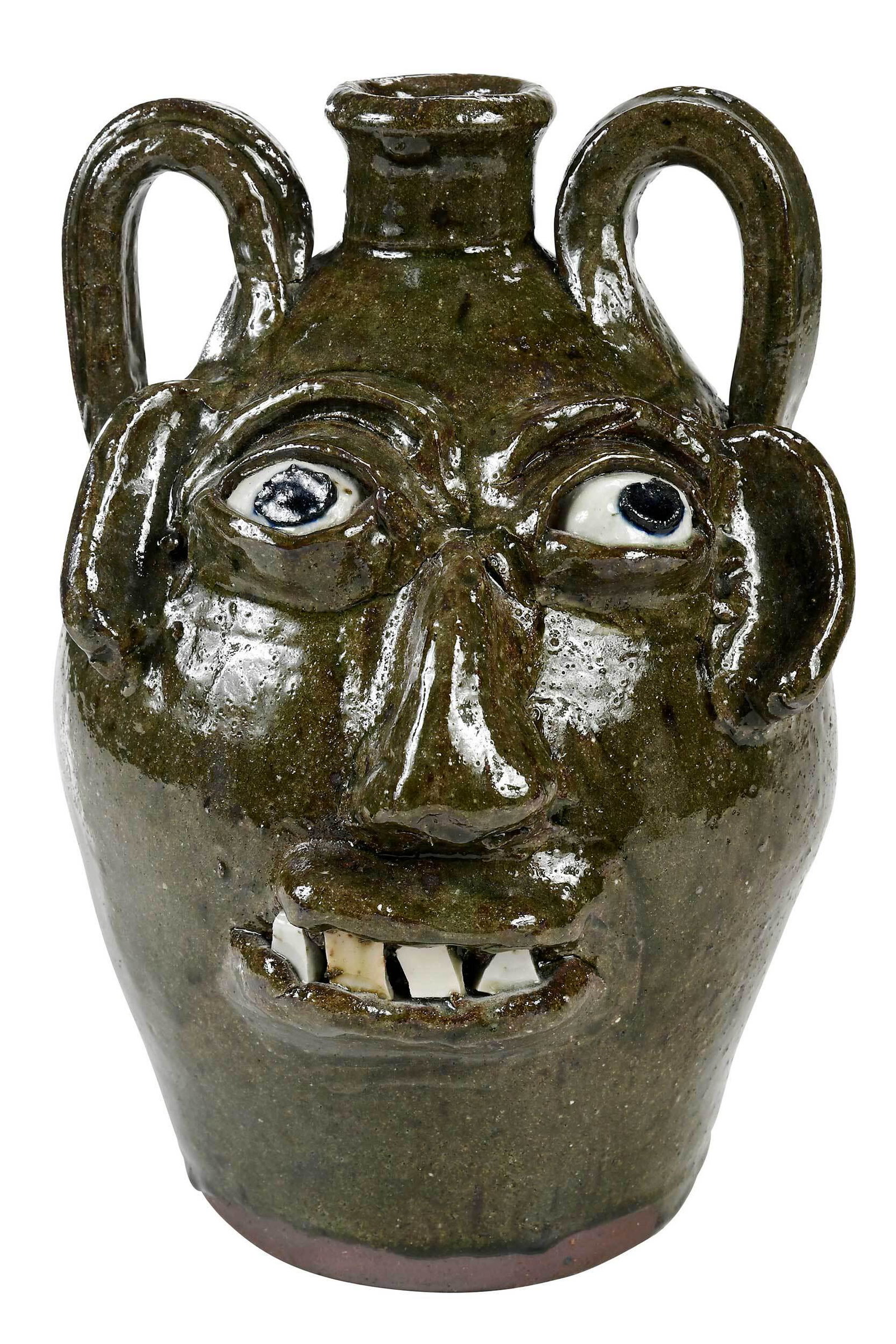 Burlon Craig Face Jug: (Vale, North Carolina, 1914-2002) light green olive glaze, applied facial feature, kaolin inset eyes, cobalt pupils, broken china teeth, several bands of wavy line decoration to back of jar, two appli