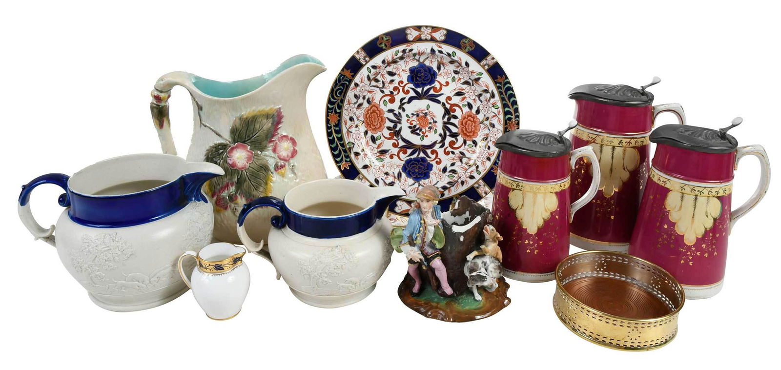Group of Eleven Decorative Table Articles: British, 19th/20th century, comprising: majolica pitcher; porcelain figural group depicting a hunt; Spode creamer; gilt metal wine coaster; two Imari Crown Derby dinner plates; two cobalt and bisque r