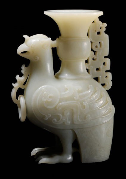 Jade Phoenix Vessel: Chinese, very pale and even-toned celadon, finely carved archaistic phoenix, the eared fowl standing firmly on powerful feet and bearing a [gu] vase with dragon handle on its back, stylized wings in f