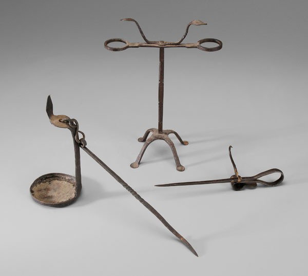 Three Wrought Iron Lighting Devices: American or Continental, probably 19th century: one with two looped holders above square shaft with extensive crosshatching and herringbone decoration, four decorated penny feet, 14 in.; spike candleh