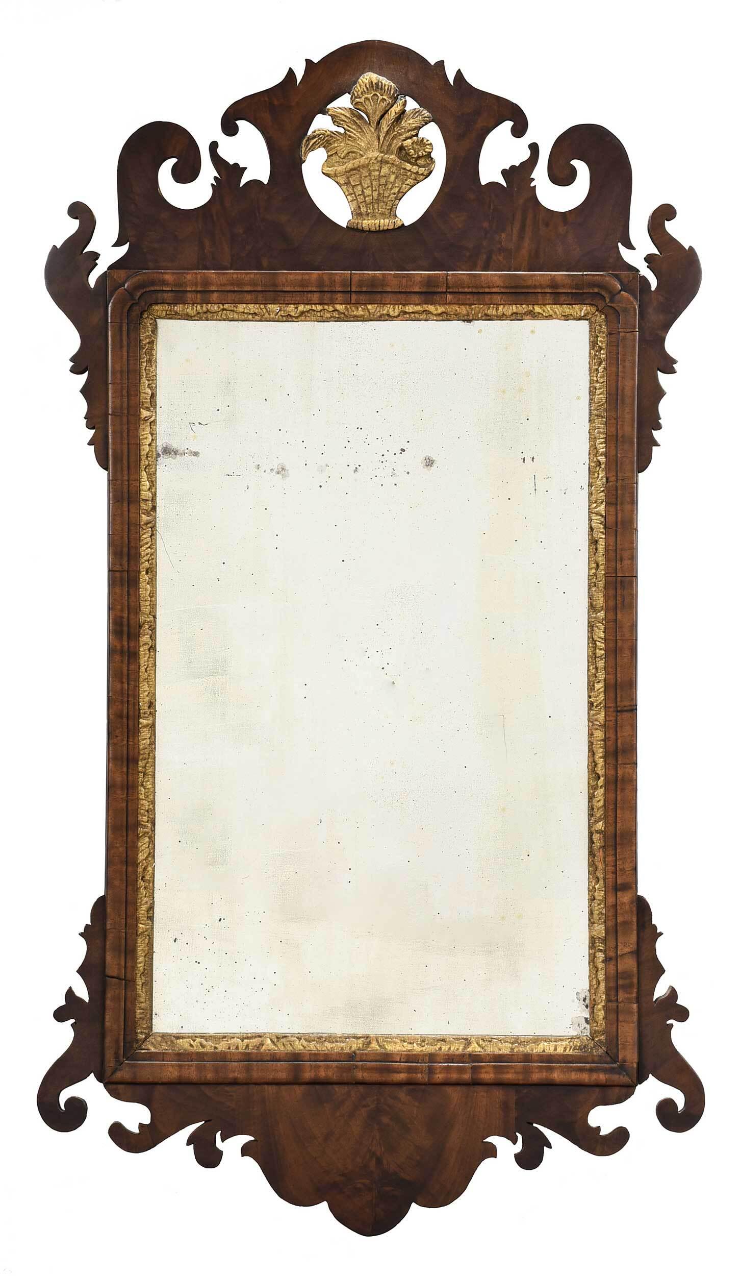 Chippendale Figured Walnut and Parcel Gilt Mirror: American/British, late 18th century, highly figured bookmatched veneers, scrolled crest centering carved and gilt basket of flowers, distressed mirror plate with carved and gilt surround, 37 x 20-1/2 
