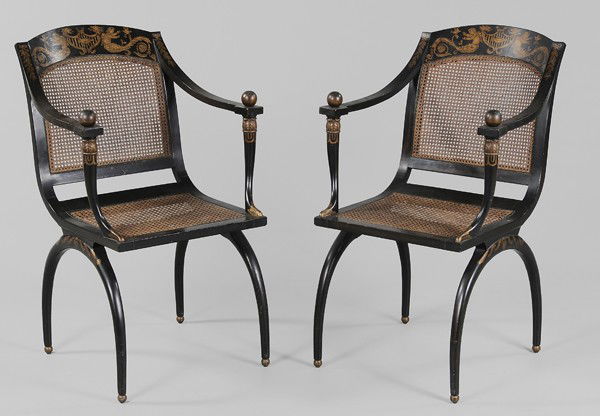 Fine Pair Madeleine Castaing Armchairs: 20th century, attributed to Madeleine Castaing, in the Empire taste with cane backs and seats, gold-painted ormolu style decoration on ebonized ground, cornucopia-form arm supports and klismos bases,