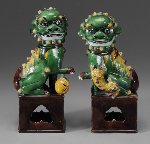 Pair Buddhist Lions: Chinese, probably early 19th century: mounted on plinths, one with ball under foot, other with clinging cub, brown and green glazes throughout, 14-1/4 in., one with base repairs, scattered small chips