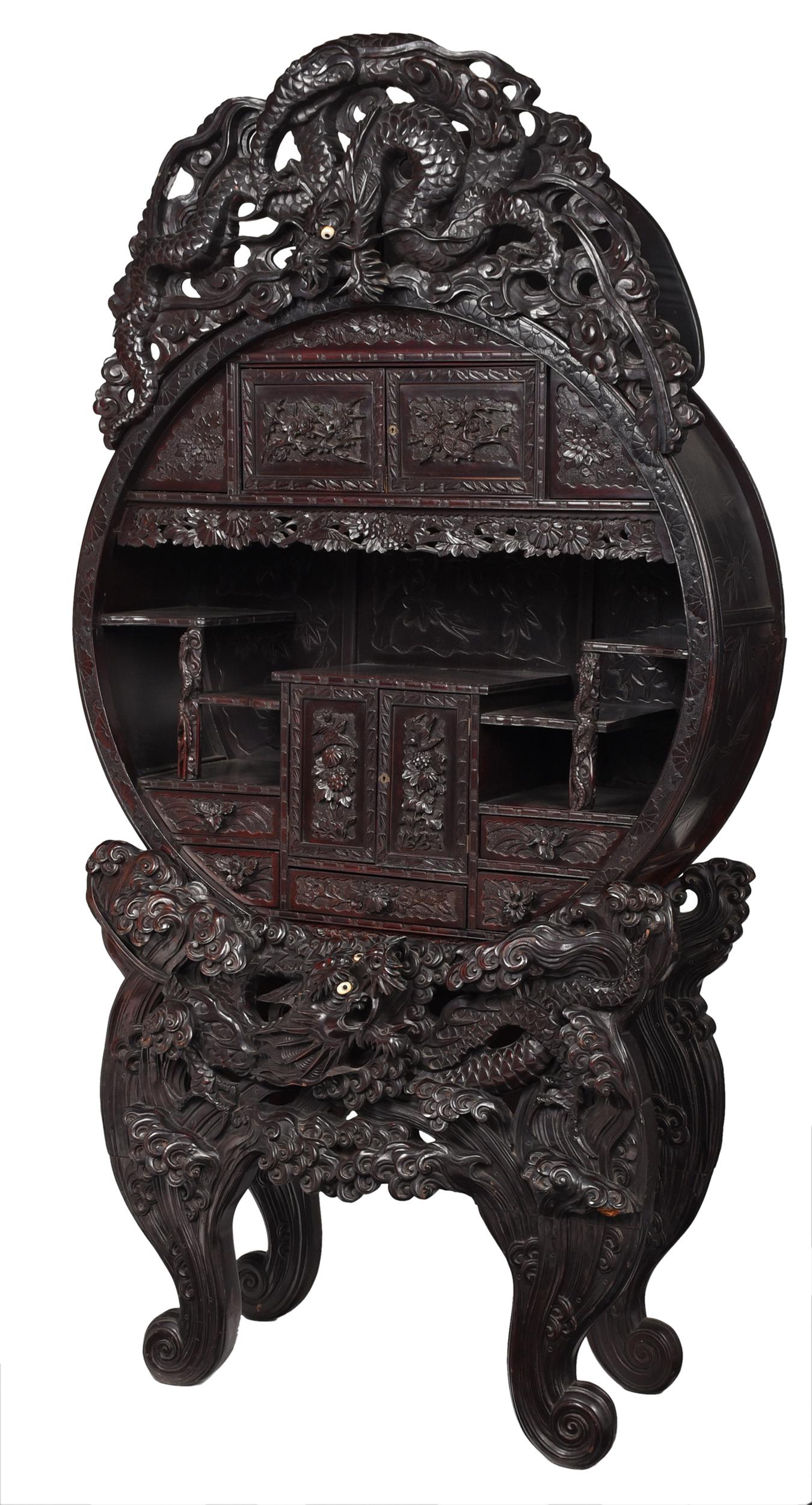 Impressive Chinese Dragon Carved Moon Cabinet: late 19th century, in reddish brown lacquered surface, with dramatic pierced carved dragon crest with inset mother of pearl and bone eyes, relief carved moon cabinet fitted with drawers, dragon and sw