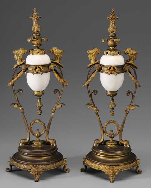 Pair French Baroque Style Gilt Metal: and Porcelain Urns Continental, 19th century, urn-shaped frame with gilt bronze mounts, hoof feet and female head mounts over gilt metal base with scrolled feet and floral and leaf borders, central wh