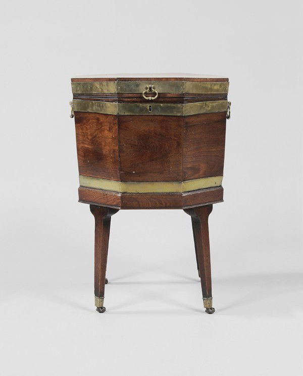 Regency Mahogany Wine Cooler: British, 19th century, octagonal form with figured mahogany veneers and brass banding, original tapered square legs with brass casters, interior with metal liner, 27 x 17-1/2 x 18 in., generally good