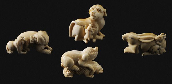 Four Japanese Style Netsukes: Chinese, 20th century, inked ivory animal groups: dog with pup beside, two rabbits, pig on badger(?), dog with climbing pup, all with finely carved bottoms, lengths 1-5/8 in. to 1-7/8 in., good condit