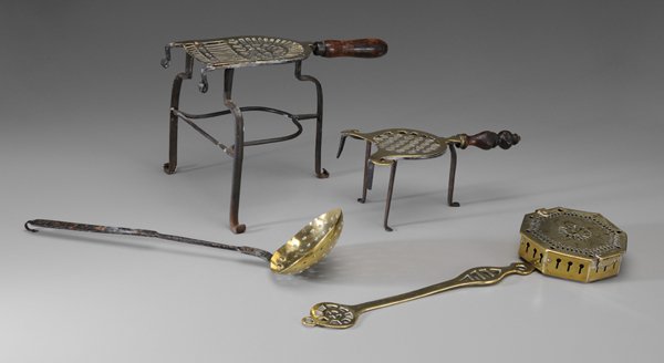 Four Brass Hearth Accessories: British, 19th century: two brass trivets with iron frames, turned wooden handles, one brass lyre-shaped trivet, 5 in., [one break in openwork platform,] and 10-1/2 in.; brass skimmer, 19-1/2 in., [min