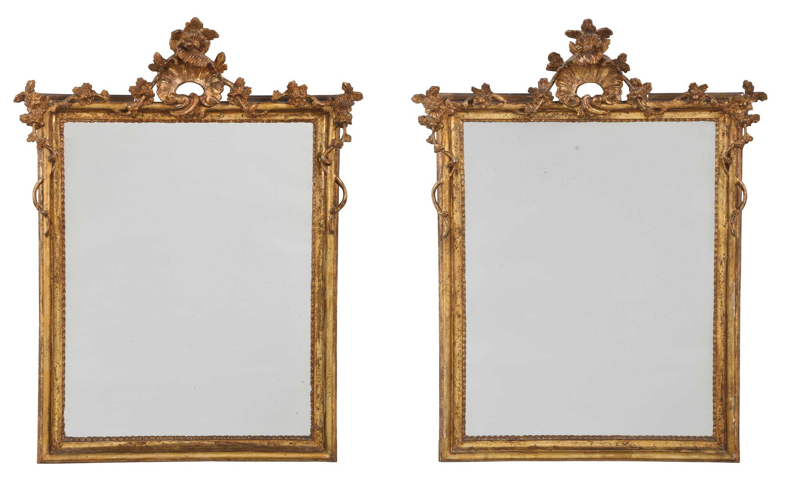 Pair of Italian Rococo Giltwood Mirrors: 19th century, floral and rocaille pierced crest, floral and vine decoration, molded mirror surround with scalloped interior border, 33 x 23 in.; accompanied by a conservation treatment report from Wil