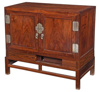 Chinese Paktong Mounted Huanghuali Cabinet on Stand: 19th century with later elements, paneled doors, Paktong nickel copper alloy hardware, interior with loose drawers, shelves, and other components, later faux papered frieze, paneled stand, includes Ro