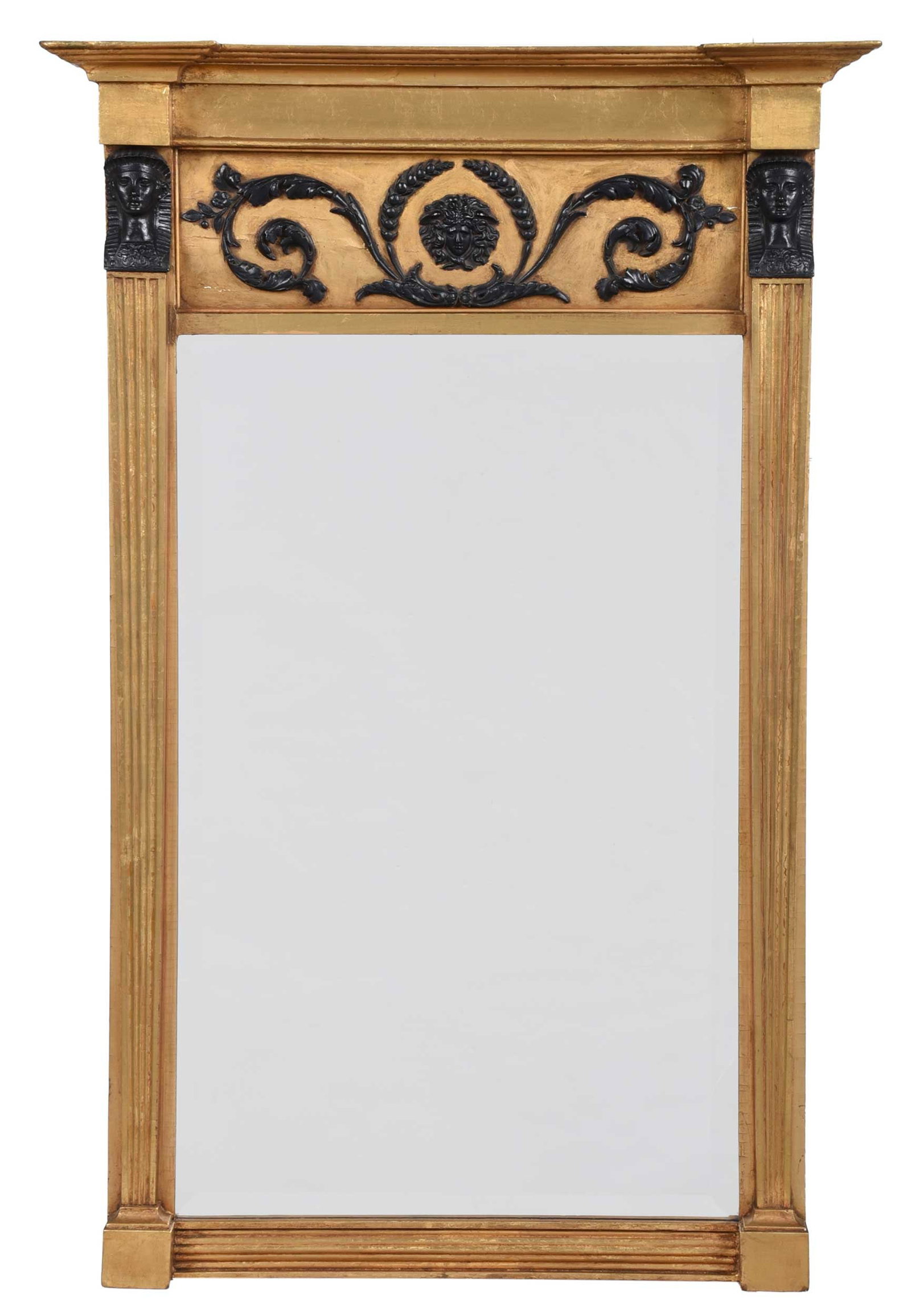 Classical Egyptianesque Parcel Painted and Giltwood Mirror: early 19th century, stepped cornice and blocked frieze, fluted stiles surmounted by Pharaoh busts flanking a foliate panel over a beveled mirror plate, reeded base, 44 x 28 in. Provenance: Private Col