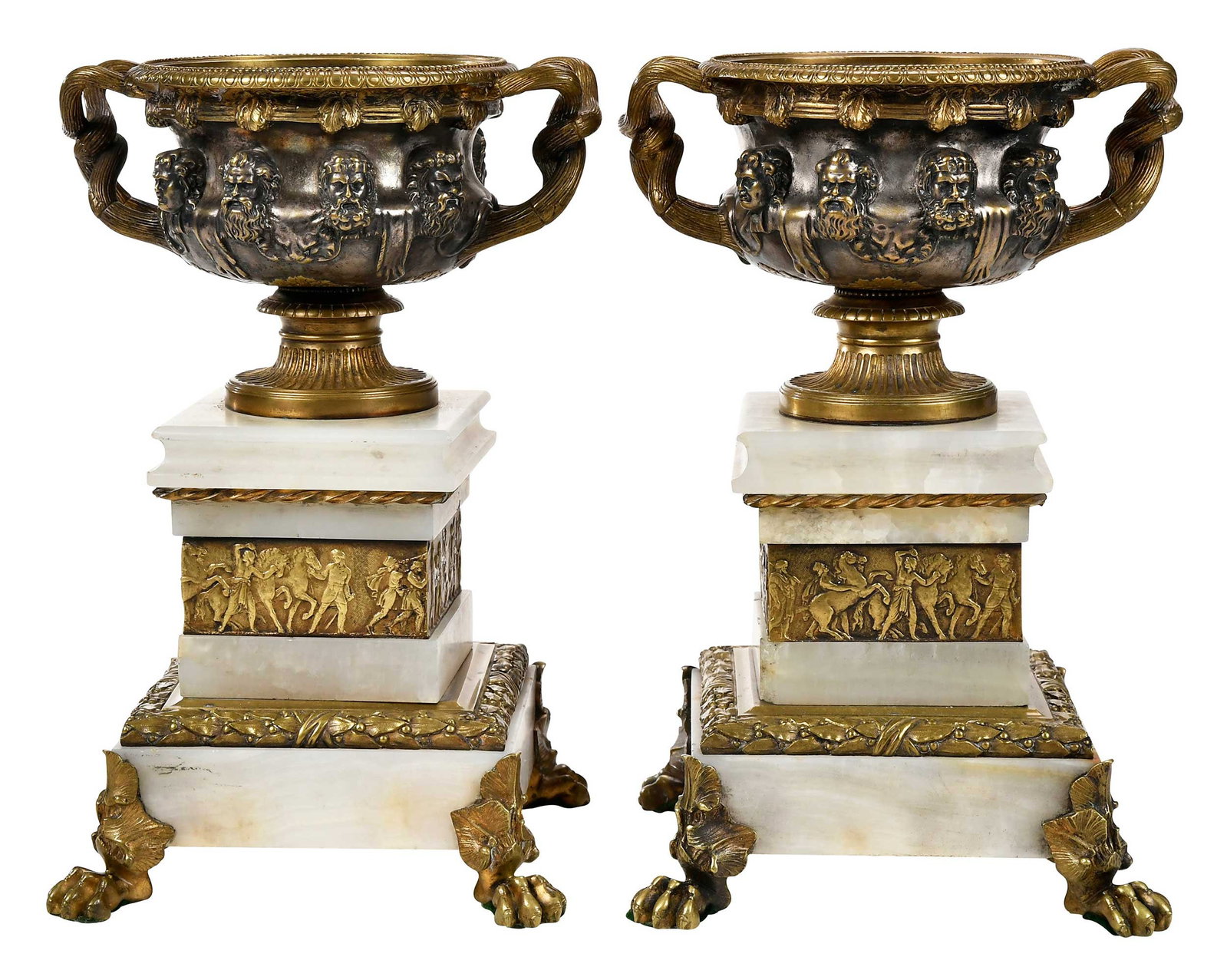 Pair Neoclassical Style Bronze and Marble Urns: Continental, each gilt bronze urn with twisted branch side handles and mask form decoration atop tiered variegated white marble bases with bands of Classical figures, on paw feet, 12-1/4 x 7-1/2 in. P