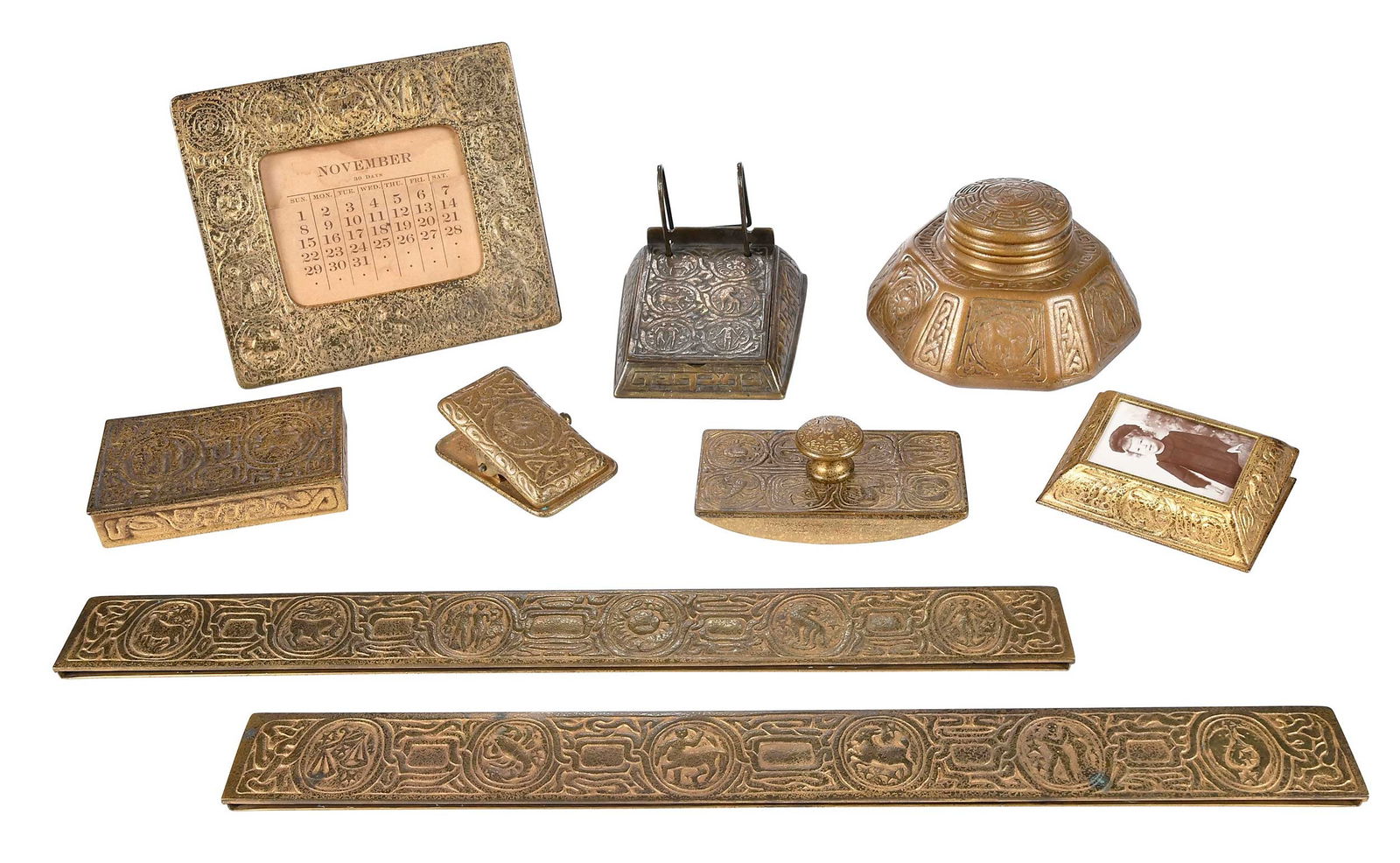 Tiffany Studios Zodiac Bronze Eight Piece Desk Set: American, late 19th/early 20th century, Tiffany Studios marks, comprising: inkwell, ink blotter, blotter ends, memoranda calendar, calendar frame, desk calendar, letter clip, and utility box, lar