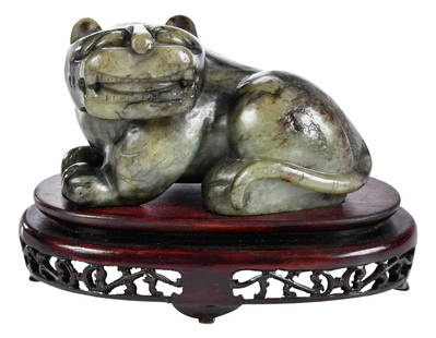 Chinese Carved Green Mottled Jade Tiger on Stand: 3 x 4-1/2 x 3 in., with conforming wood stand, 4-1/4 x 6 x 3 in. on standNote: This item tested as jadeite on the Presidium Gem Tester II.