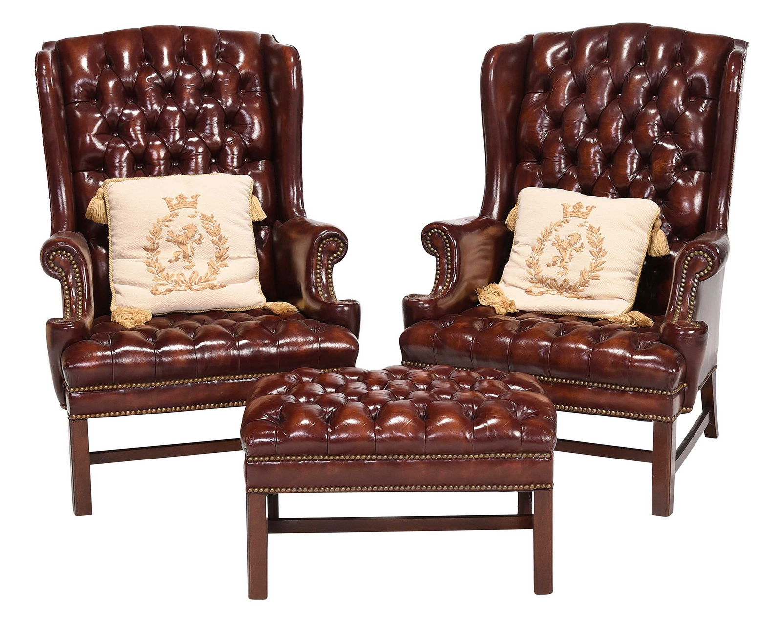 Pair of Modern Tufted Brown Leather Wing Chairs with Ottoman: modern, labels for Hickory Chair Company (accompanied by a catalog in which one is pictured), tufted reddish brown leather with brass tacking, with two loose cushions with tassels, 44 x 31 x 27 in. Pr