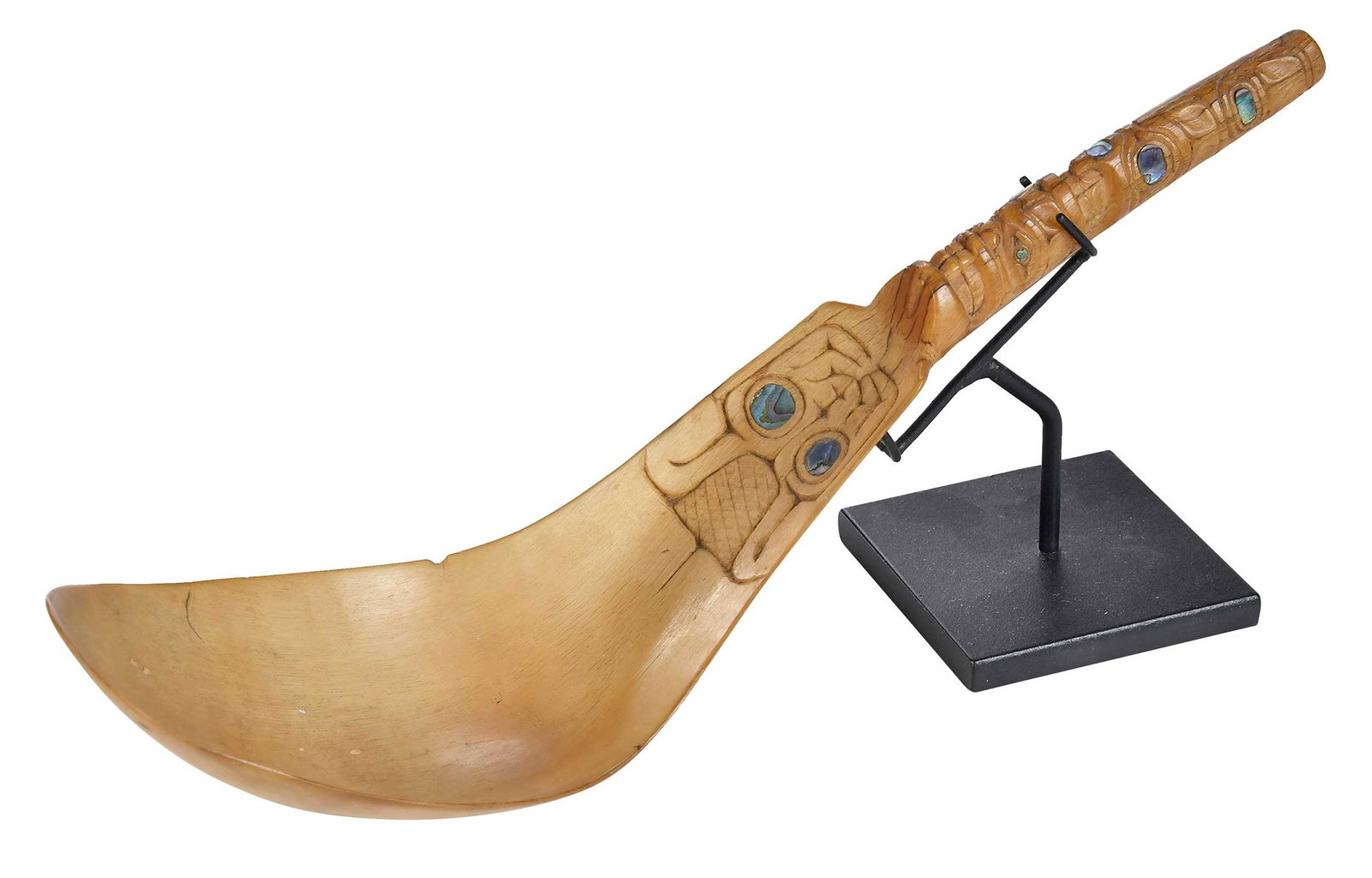 Northwest Coast Carved Horn Spoon: possibly Haida, carved and incised handle and ladle, with inset abalone, 13 x 3-1/2 in.; with bespoke iron stand