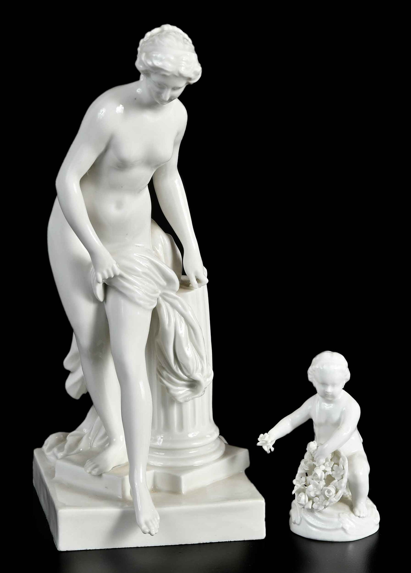 Two Meissen Porcelain Figures: German, late 19th/early 20th century, crossed swords in blue underglaze to bases, includes La Baigneuse figure and cupid with flower basket, larger 10 x 5 x 4-3/4 in. Provenance: Estate of Gary L. Joh