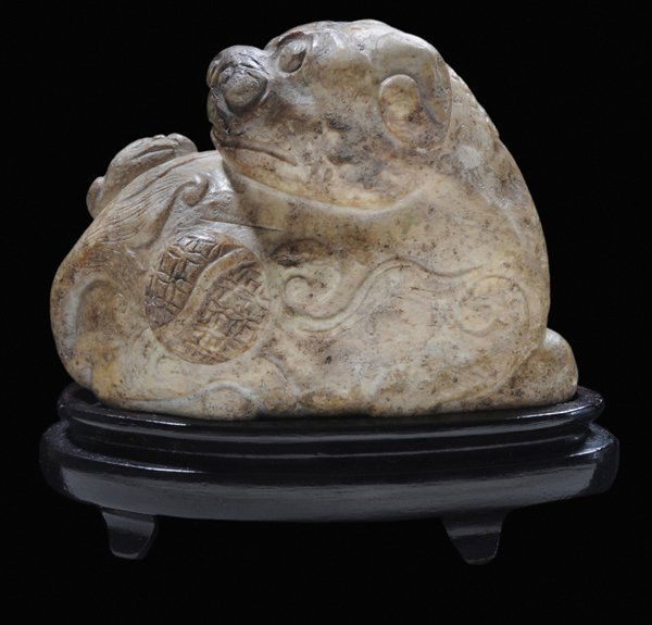 Carved Jade Fu Lion: Chinese, late 19th/20th century, nephrite, mottled tan, with worsted ball, baby lion on back of mother, pebble form, 3 x 4 in.; with fitted wood stand, low to no polish, otherwise good condition. Prov