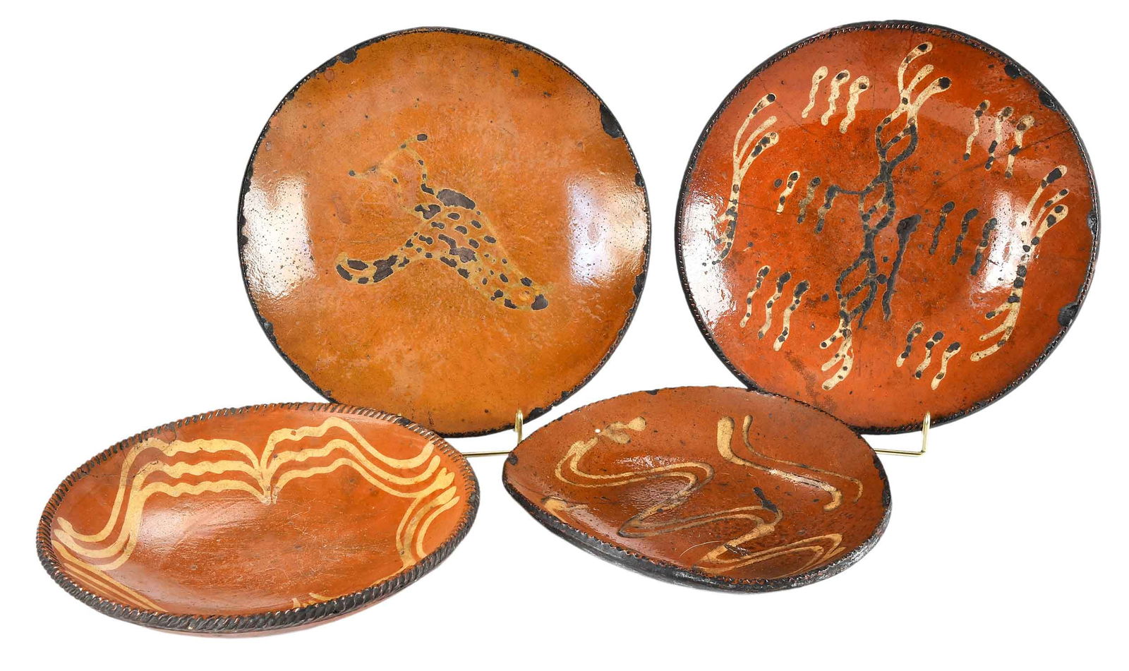 Four Early American Slip Decorated Redware Plates: late 18th to early 19th century, likely made in Pennsylvania, each of similar form with wavy line decoration, one with bird design, largest 2 x 11-1/4 x 11-1/4 in. Provenance: Estate of Joe and Betsy